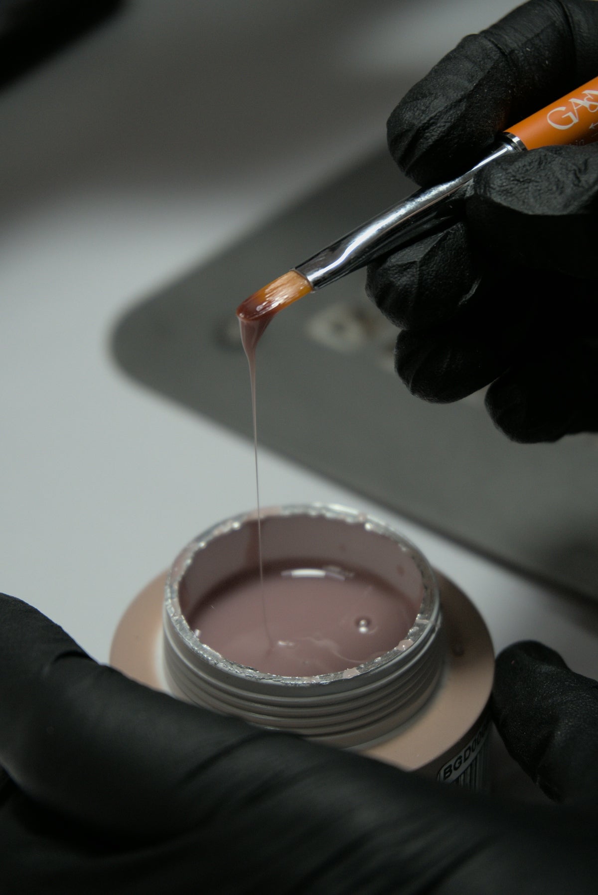 A person in a black glove is dipping something into a bowl