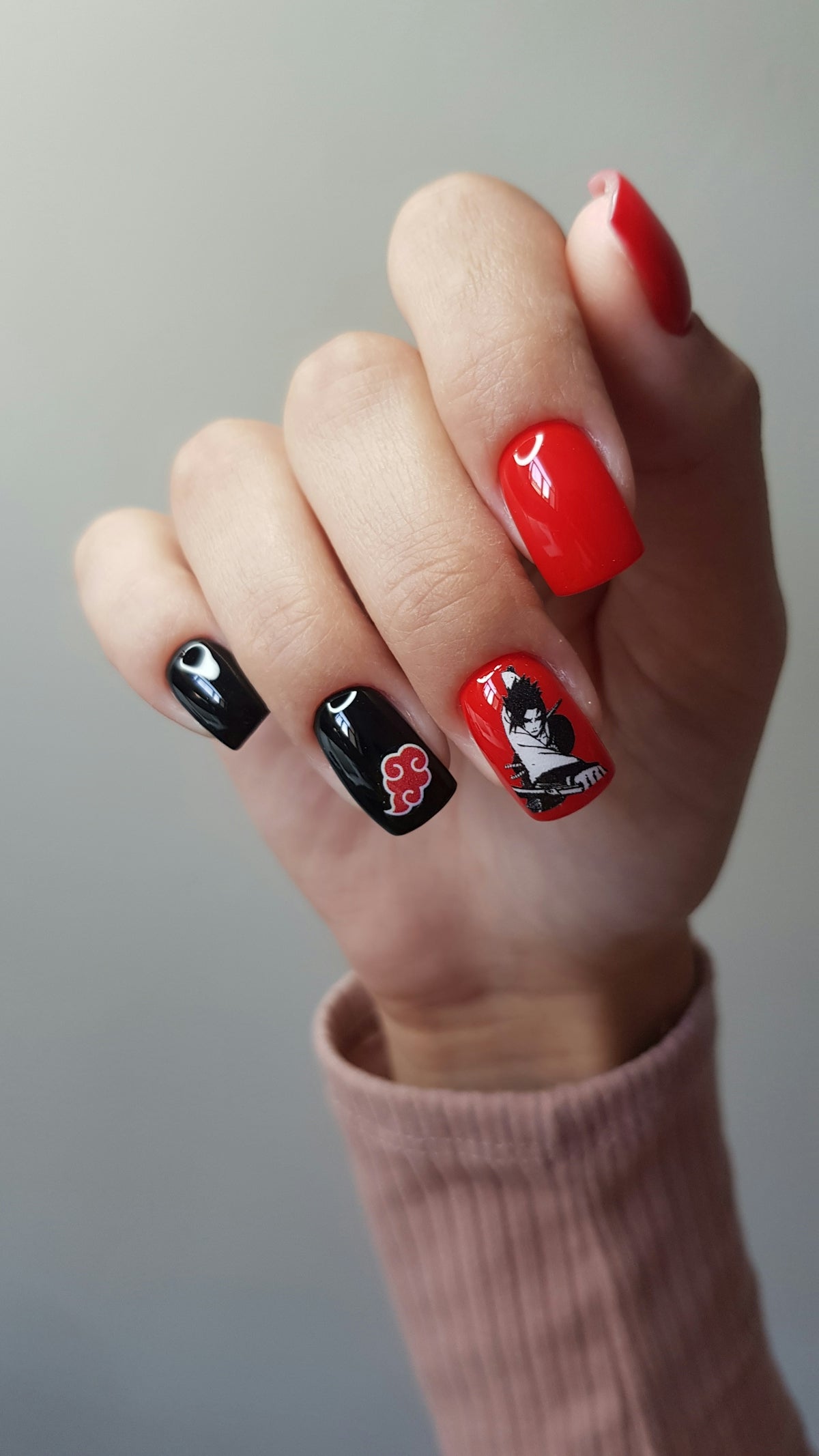 Hand with black and red nails featuring anime characters.